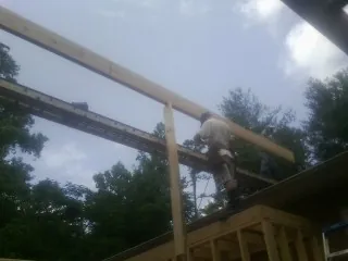 Carpenter setting a ridge beam over a new addition frame — Ice Dam Removal by Roofing Brothers in Long Island City