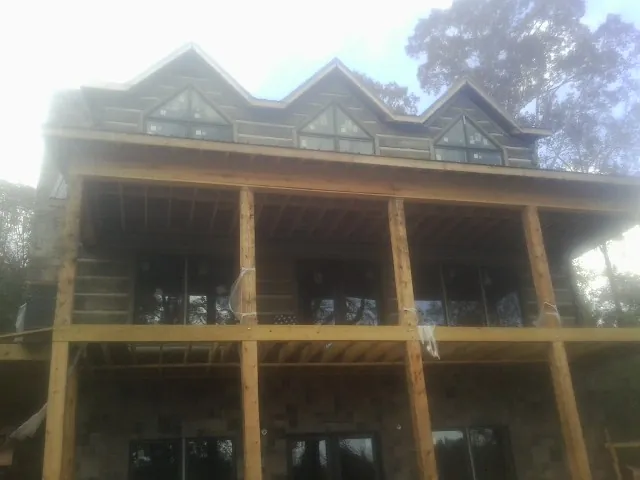 Dormers and porch framing on a large log home under construction — Roof Coating work by our crew in Long Island City