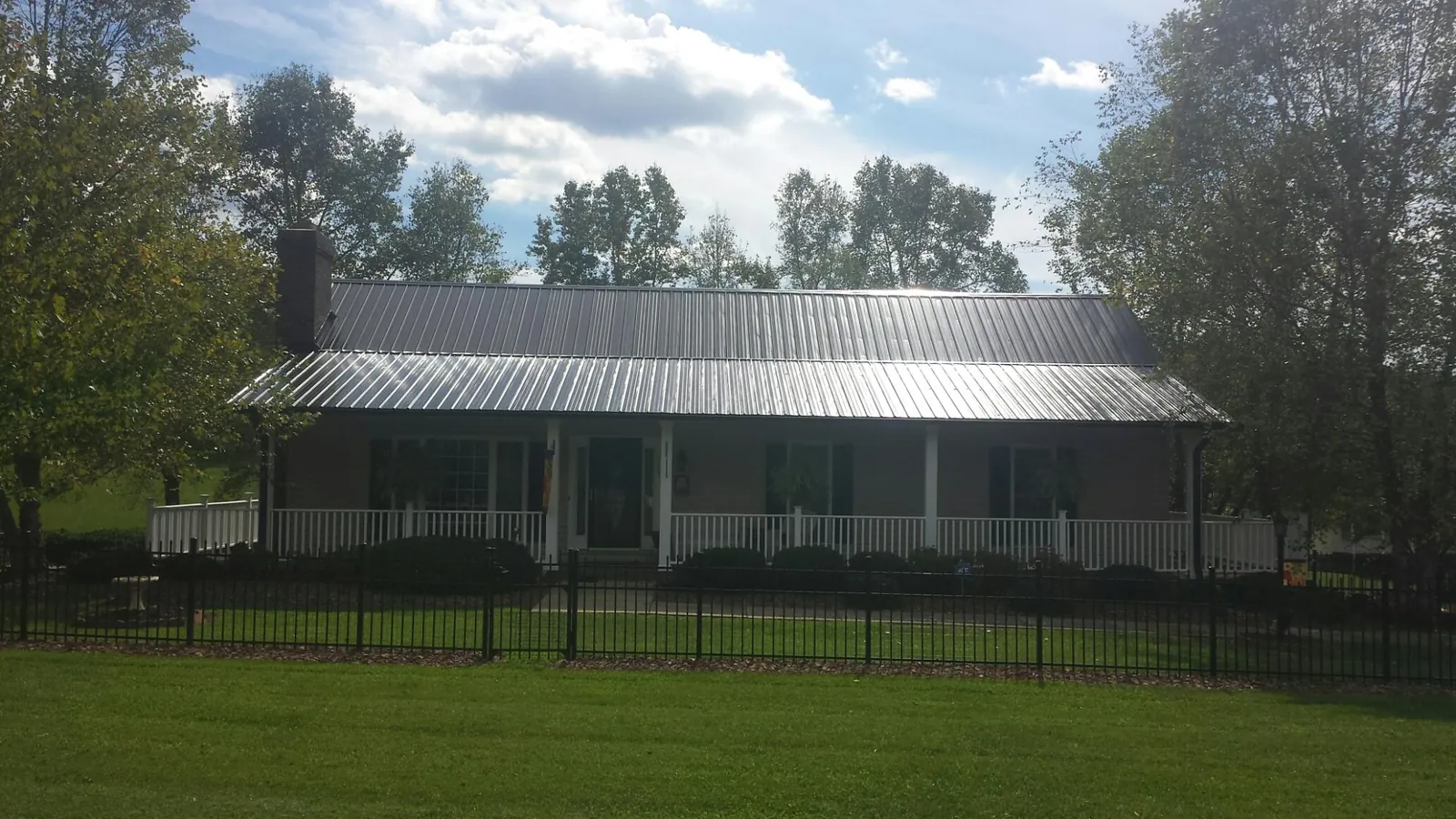 Gray metal roof on a brick ranch with a full width front porch — Gutter Guard Installation work by our crew in Long Island City