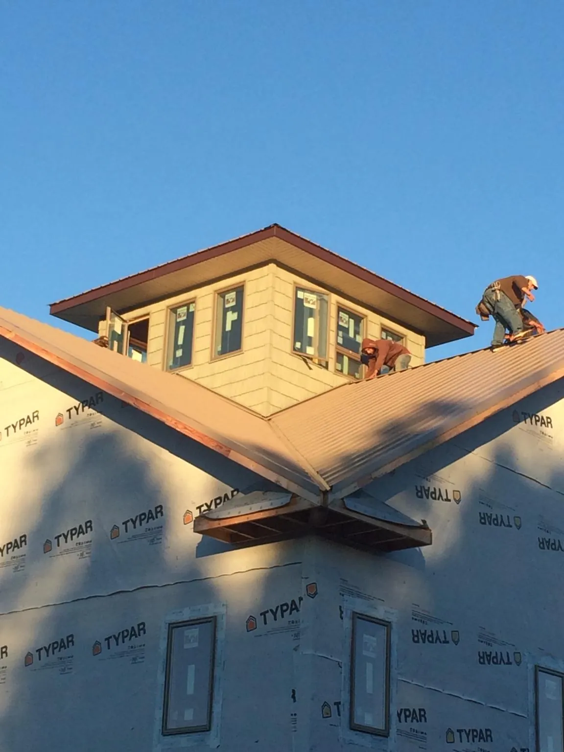 Roofers working around a rooftop cupola on a new metal roof at sunset — Roof Waterproofing in Long Island City by Roofing Brothers
